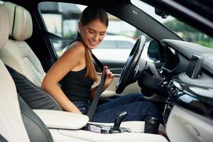 Wearing safety, belt. Woman is sitting in the car photo