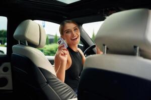 Showing off, with ,the driver's license. Woman is sitting in the car photo