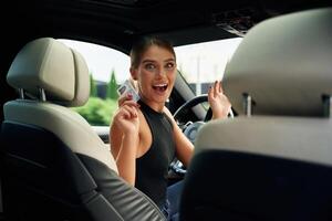 Showing off, with the driver's license. Woman is sitting in the car photo