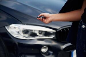 Focused,, close up view of woman hand that is holding key in front of the car photo
