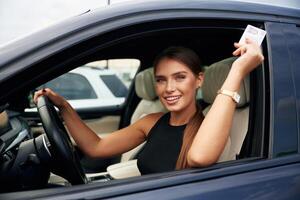 Showing, off with the driver's license. Woman is sitting in the car photo