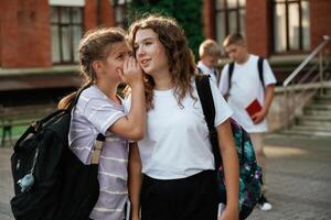 Gossip about ,the boys. Kids ,are, nea,r the ,school together, pupils photo