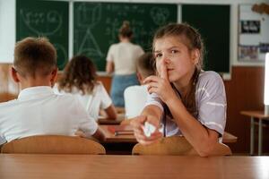 Girl is, gives a,, cheat sheet. Pupils, kids in the classroom together photo