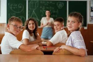 Teacher, is, at,, work. Pupils, kids in the classroom together photo