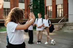 Standing, and posing. Kids are near the school together, pupils photo
