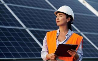 Notepad, in, hands. Female worker engineer in ,uniform is near solar panels.. photo