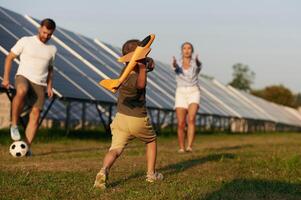 Wellness, with, toy plane. Father,, mother, and little son are outdoors near solar panels photo