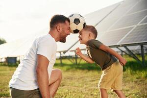 Soccer ball on heads,,. Father, with his little son are together near the solar panels photo