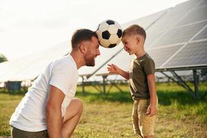 Soccer, ball on heads. Father with his little son are together near the solar panels photo