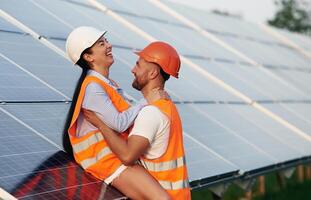 Playful ,,,,mood, embracing each other. Man and woman, workers are near solar panels, in uniform photo