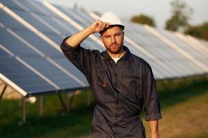 Handsome guy portrait. Man is working with solar panels outdoors at daytime. photo