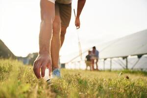 Tranquil,, playing badminton. Father, mother and little son are outdoors near solar panels photo