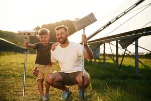 Front view, ready to clean the surface. ....Father with his little son are together near the solar panels photo