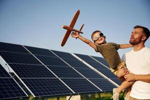 Aviator glasses and toy plane.. Father with his little son are together near the solar panels photo