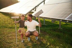 Front view, ready to clean the,,, surface. Father with his little son are together near the solar panels photo
