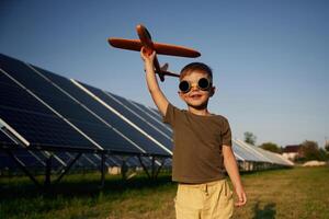 Time, to, fly. Aviator glasses and toy plane. Little boy is with solar panels outdoors photo
