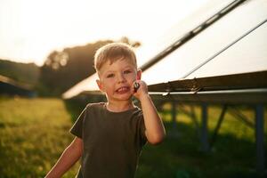 Little, bo,y is with solar panels outdoors photo