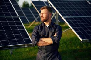 Portrait, standing with arms,,, crossed. Man is working with solar panels outdoors at daytime photo