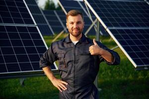 Portrait, standing with arms crossed., Man ,is working with solar panels outdoors at daytime photo