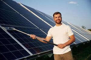 Mop,,, in ,hands. Man is working with solar panels outdoors at daytime photo