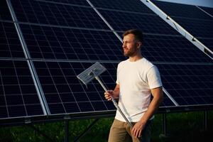 Mop in hands. Man is working ,with solar panels outdoors at daytime photo