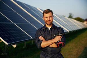 Taking a break, standing... Man is working with solar panels outdoors at daytime photo