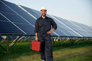 Case in the hand. Man is working ,,with solar panels outdoors at daytime photo