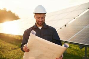 Paper ,plan, in ,,hands. Man is working with solar panels outdoors at daytime photo