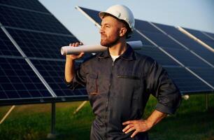 Taking a break, ,standing. Man is working with solar panels outdoors at daytime photo