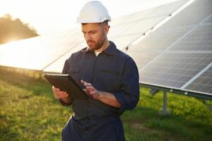 Reflection of the sunlight behind. .Man is working with solar panels outdoors at daytime photo