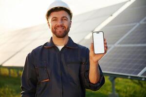 Smartphone ,,with ,copy space on it. Man is working with solar panels outdoors at daytime photo