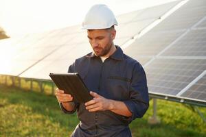 Reflection, of the sunlight behind... Man is working with solar panels outdoors at daytime photo