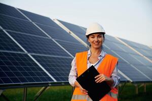 Female worker engineer ,in uniform, is near solar panels photo