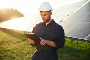 Reflection, of ,the, sunlight behind. Man is working with solar panels outdoors at daytime photo