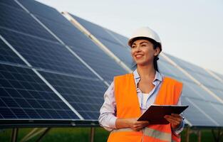 Black, notepad, in, hands. Female worker engineer in uniform is near solar panels photo