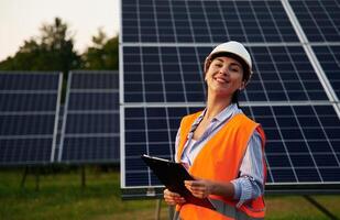 Female worker ,,engineer in uniform is near solar panels photo
