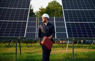 Red case in hand.. Man is working with solar panels outdoors at daytime photo