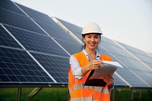 Female ,worker,, engineer in uniform is near solar panels photo