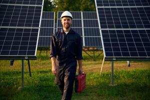 Red case, in hand. Man is working with solar panels outdoors at daytime photo
