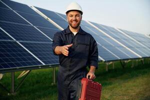 Red case in, hand. Man is working with solar panels outdoors at daytime photo