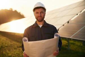 Pape,r plan in hands. Man is working with solar panels outdoors at daytime photo