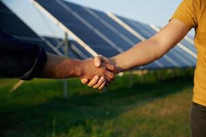 Close up, view of handshake against solar panels outdoors photo