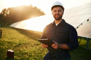 Reflection, of the sunlight behind. Man is working with solar panels outdoors at daytime photo