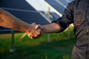 Close up ,view of handshake against solar panels outdoors photo