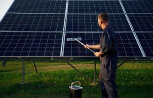 Side, view, cleaning,, service. Man is working with solar panels outdoors at daytime photo