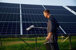 Side view,, cleaning, service. Man is working with solar panels outdoors at daytime photo