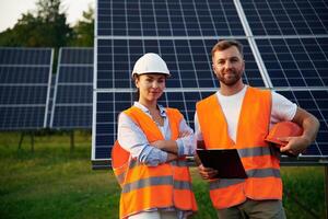 Man ,and, woman, workers are near solar panels, in uniform photo