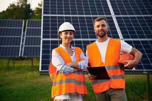 Man ,and woman, workers, are near solar panels, in uniform photo