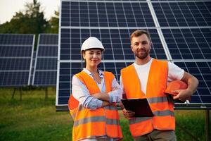Man, and woman, workers are near solar panels, in uniform photo