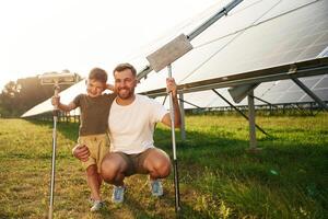 Front,, view, ready to clean the surface. Father with his little son are together near the solar panels photo